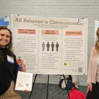 Mary Doucette and Daphnie Uhrich standing in front of their poster presentation